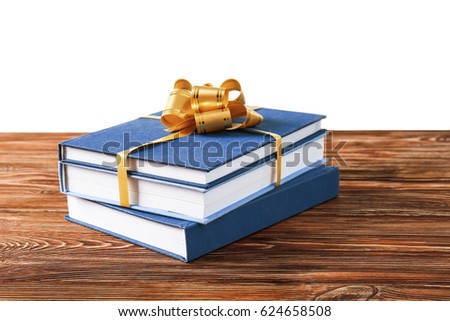 Stack of books with ribbon as gift on wooden table