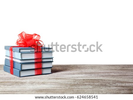 Stack of books with ribbon as gift on wooden table