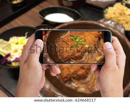Man holding smartphone taken Tonkatsu set; Japanese food photo to share social network