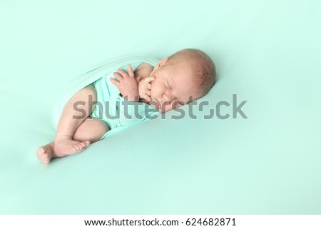 Sleeping cute newborn baby wrapped on mint background, light tone, tenderness