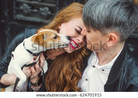 A man and a woman are walking around the city.They are holding a dog. Jack is scattered in his arms Royalty-Free Stock Photo #624701915