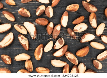 Brazil nuts are scattered on wooden background, top view
