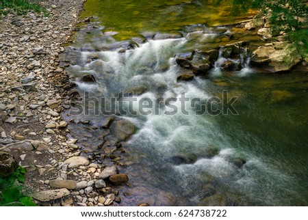 Rapid stream flow along shore covered with stone. beautiful nature view in summer time.