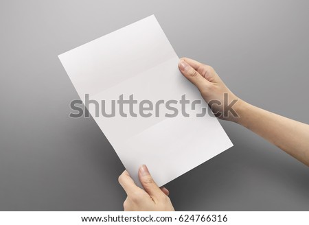 Hands holding paper blank a4 size for letter paper on grey background