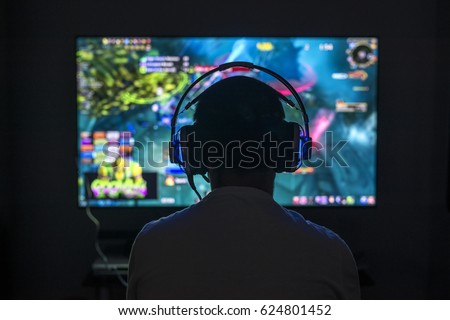 Young gamer playing video game wearing headphone.
 Royalty-Free Stock Photo #624801452