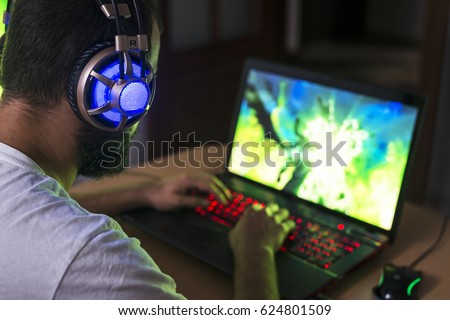 Young gamer playing video game wearing headphone.
 Royalty-Free Stock Photo #624801509