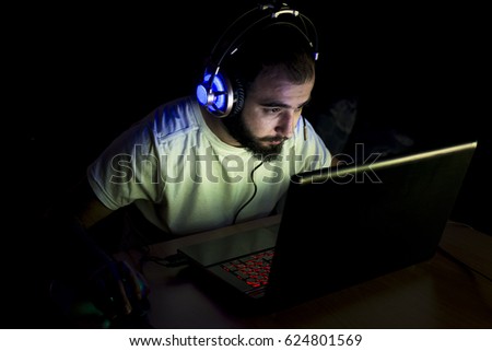Young gamer playing video game wearing headphone.
