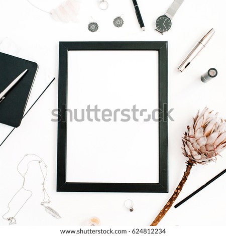 Blogger or freelancer workspace with blank screen photo frame, protea flower, notebook, watches and feminine accessories on white background. Flat lay, top view minimalistic decorated home office desk