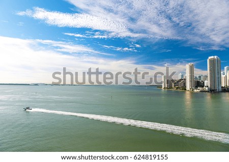 Miami skyscrapers with blue cloudy sky,white boat sailing next to Miami downtown, Aerial view