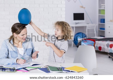 Rude boy bothering his mother sitting close Royalty-Free Stock Photo #624843260
