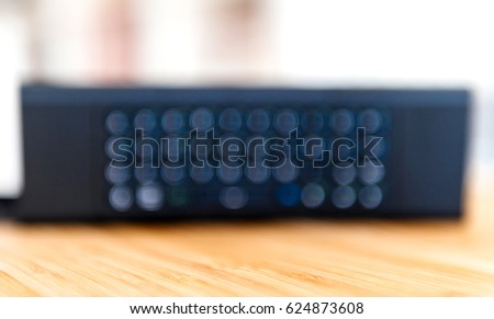 Defocused view of Modern remote control for smart tv, fiber tv modem with full qwerty alphabeth and sign keypads 