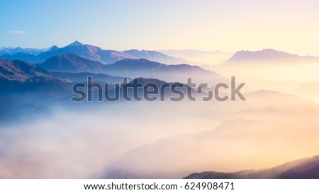 Mountain range with visible silhouettes through the morning colorful fog. Royalty-Free Stock Photo #624908471