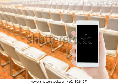 woman use mobile phone and blurred image of the rows of empty chairs in the conference room