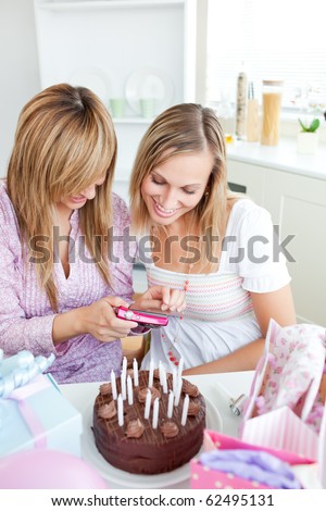 Two bright female friends looking at pictures during a birthday party in the kitchen at home