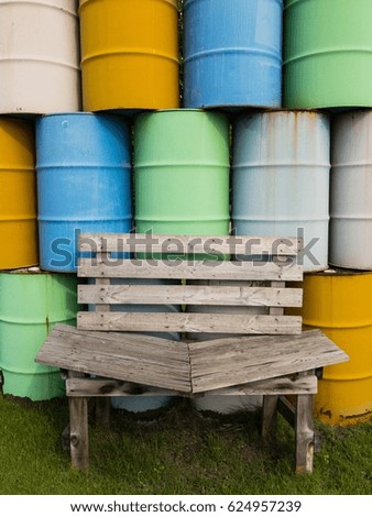 Wooden chair on the green grass with the colorful gas tank in background.