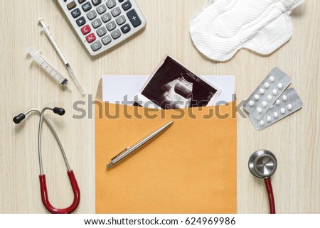 Top view of uterus via ultrasound picture in envelope with sanitary napkin, medicine, stethoscope, hypodermic syringe and calculator - dysmenorrhea concept