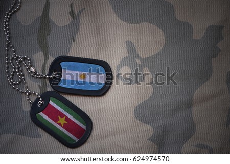 army blank, dog tag with flag of argentina and suriname on the khaki texture background. military concept