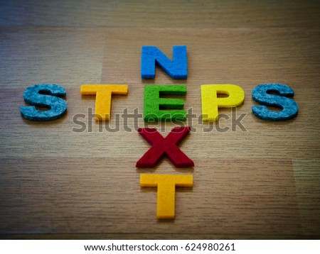 next steps concept in colorful letters on wooden blackboard
