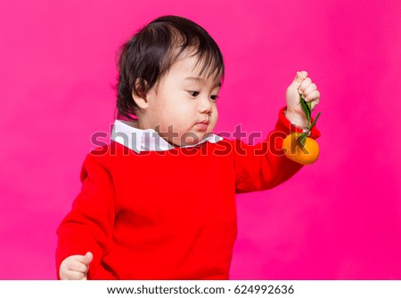 Little kid holding tangerine