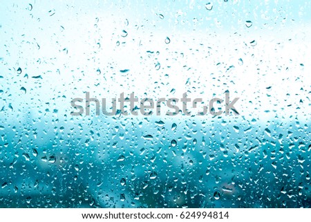Rain drops, water background of rainy day on a window glass blur light blue texture, abstract with space defocused