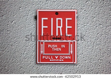 Fire alarm button on concrete wall background.