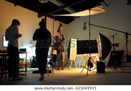 Silhouette of people working in production studio for shooting or recording by digital camera and lighting set. Royalty-Free Stock Photo #625049921
