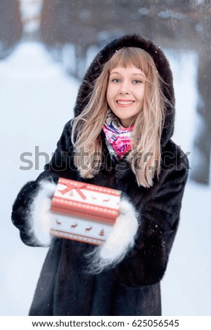 vertical picture smiling girl holding a box with a gift in a winter forest