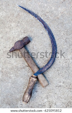 Sickle and hammer (serp i molot). Communist symbol. Farm and worker tools on the concrete surface.