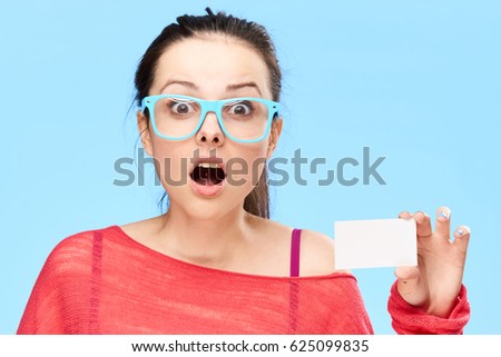     surprised oman portrait in glasses on blue background with bussines card
