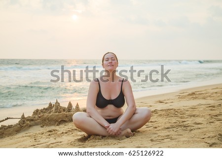 Beautiful young woman in a swimsuit resting on a tropical beach.