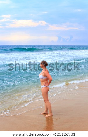 Beautiful young woman in a swimsuit resting on a tropical beach.