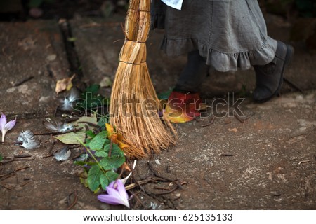 Cinderella cries in an old, dirty, torn dress, she is tired. Sweeps the floor off the bench. Preschool girl in the costume from the fairy tale by Charles Perrault. Feet, broom, dress close-up
