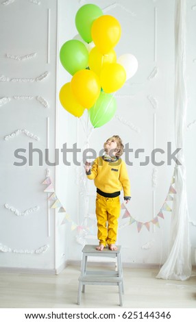 A boy is having fun and jumping with a bunch of balloons in bright clothes