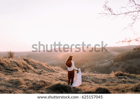 Beautiful girl with a map, binoculars and hat on top of the mountains walking at sunset. Soft focus. Back view