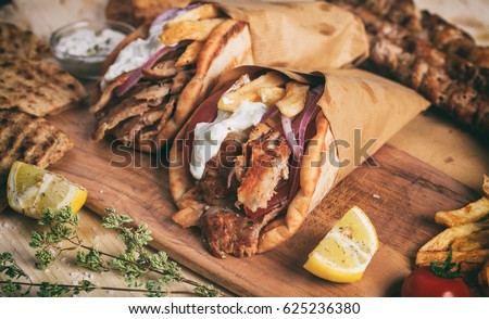 Greek gyros wrapped in pita breads on a wooden background Royalty-Free Stock Photo #625236380