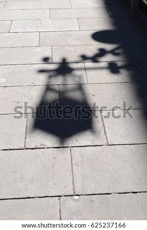 Shadow from a street lamp on a street tile