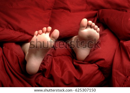 Feet in bed with red blanket people resting