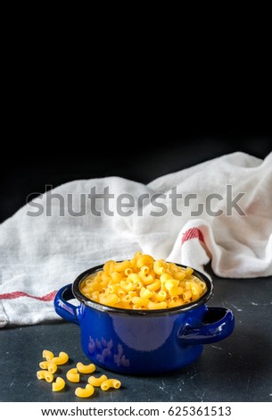 Raw macaroni in ceramic pot on black marble background,Top view background.
