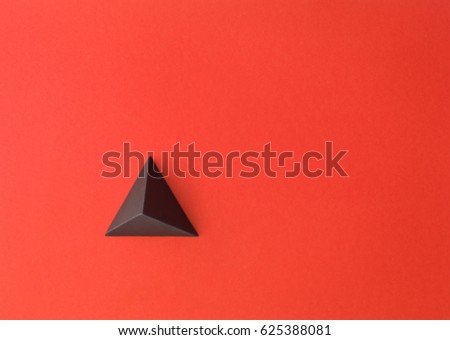 Red paper tetrahedron on red paper. Copy space available. Usefull for business cards and web