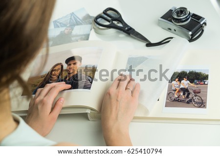 Looking at family wedding photo album. Young female engaged or married person turns pages and selects images for photo album Royalty-Free Stock Photo #625410794