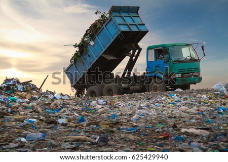 Dump truck unloading waste on a landfill Royalty-Free Stock Photo #625429940