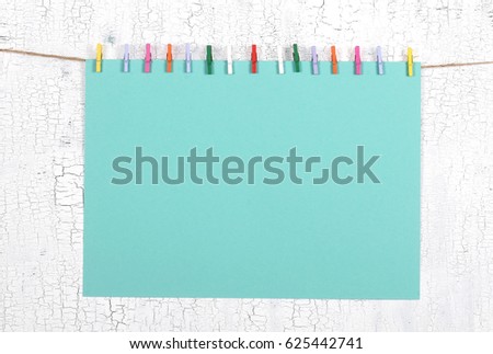 A sticker for notes on a light background is attached to small clothespins