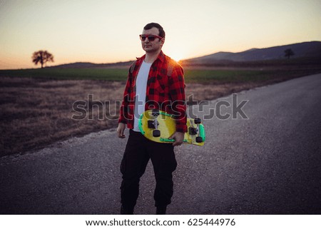 Man outdoors holding skateboard on the street