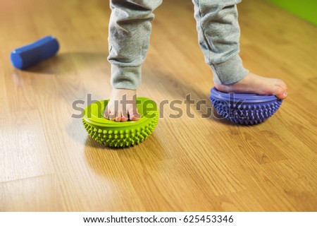 Flat feet correction exercise. Little boy walking over spiked half balance massage balls