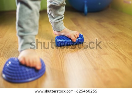 Flat feet correction exercise. Little boy using spiked rubber roller