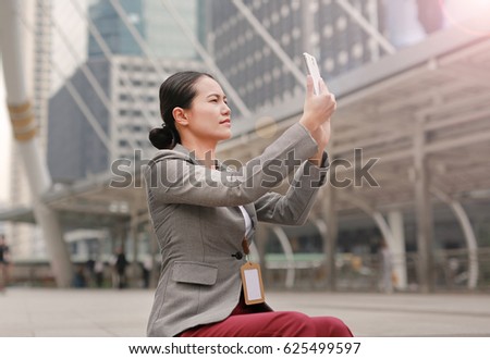 Beautiful business woman sitting and using a smartphone taking photo around.