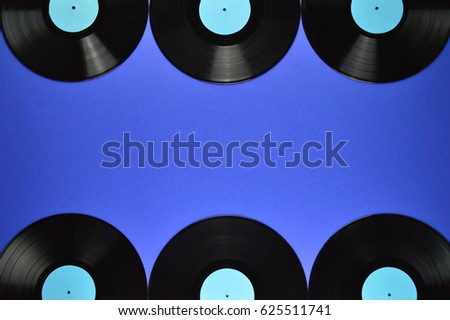 border of old black vinyl records on blue background