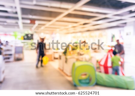 Blur picture newborn section display showroom in furniture mall. Vivid kid playing room, play corner. Colorful tunnel, eco-friendly wooden table chair set, bed, circus tent, flag strip. Vintage tone.