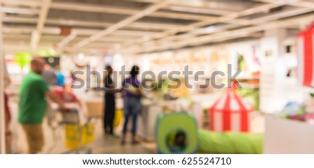 Blur picture newborn section display showroom in furniture mall. Vivid kid playing room, play corner. Colorful tunnel, eco-friendly wooden table chair set, bed, circus tent, flag strip. Panorama style