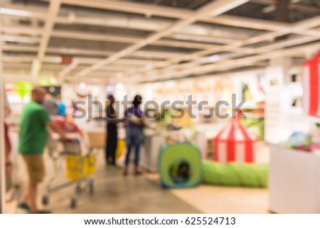 Blur picture background of newborn section display showroom in furniture mall. Vivid kid playing room, play corner. Colorful tunnel, eco-friendly wooden table chair set, bed, circus tent, flag striped